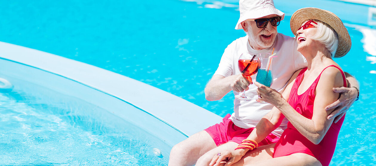 Sommer schöner Urlaub Senioren Ehepaar isst Eis am blauen Pool 